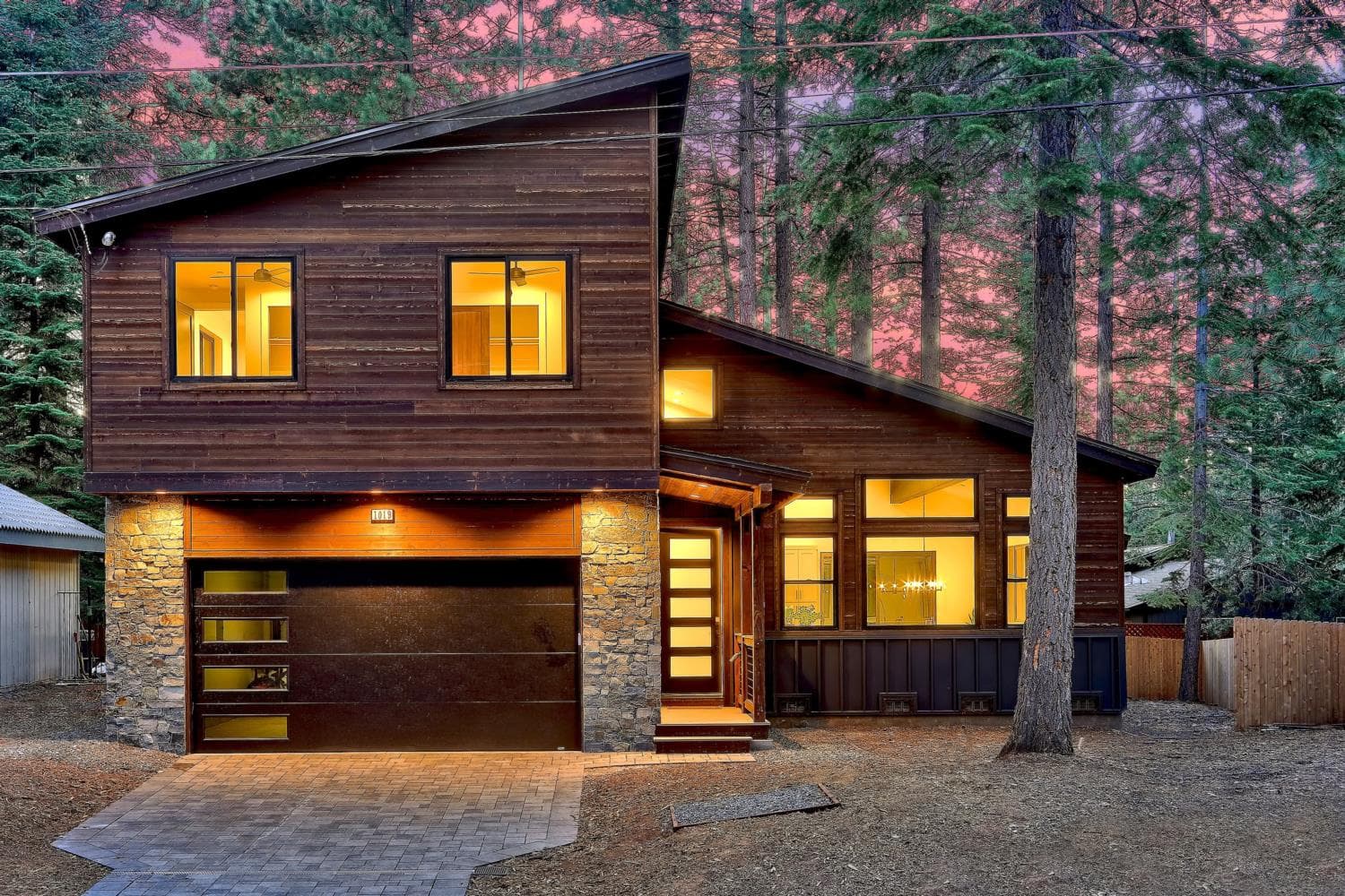 Custom home exterior at dusk, warm interior lights glowing against an alpenglow sky.