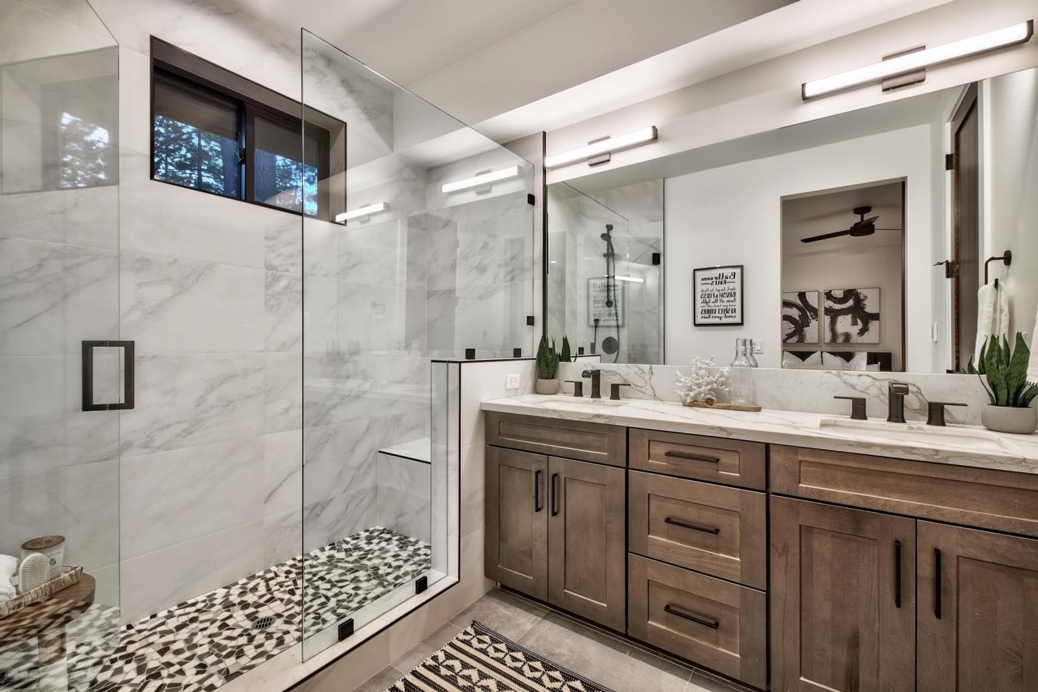 Primary bathroom in marble with a glass walk-in shower and a double vanity.