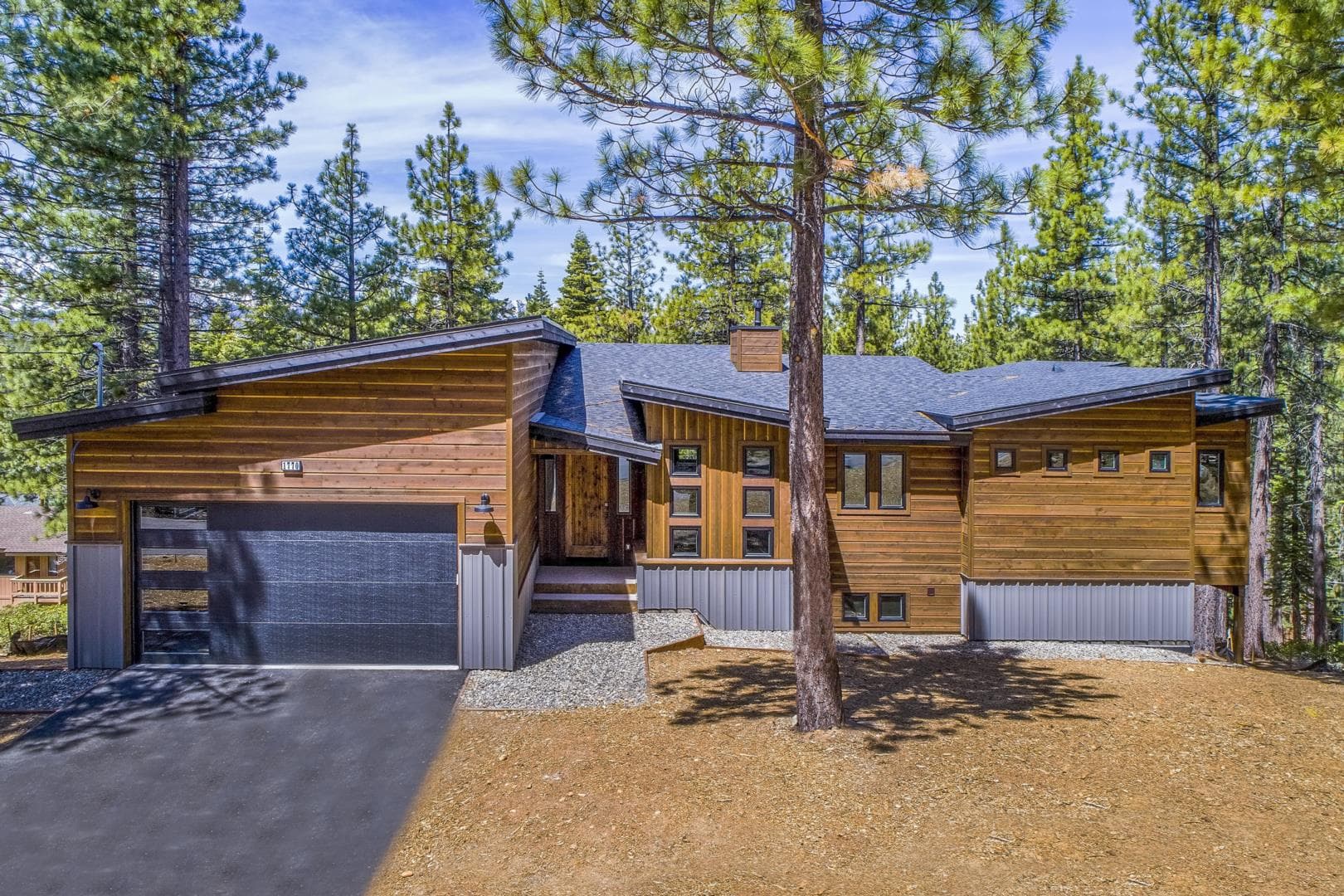 Cedar-sided custom home set among tall pines on a sunny day.